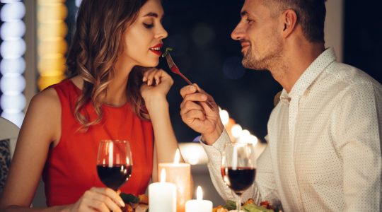 mężczyzna karmi piękną kobietę przy romantycznej kolacji w domu